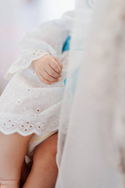 A baby doll with a lace outfit is positioned softly in a setting with gentle lighting. The doll's hand is visible, showcasing details of the fabric and design.