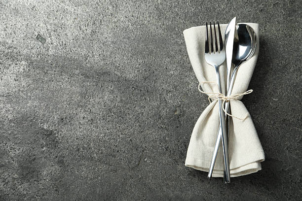 Stylish silver cutlery and napkin on grey table, top view. Space for text