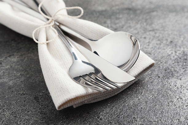 Stylish silver cutlery and napkin on grey table, closeup