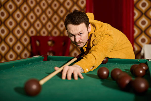 Two friends play pool in a cozy pub setting, one leaning to take a precise shot. Warm lighting, casual mood, and a sense of competition and camaraderie.