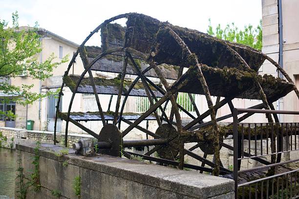 Water wheel rotating, producing energy from stream in lush green forest