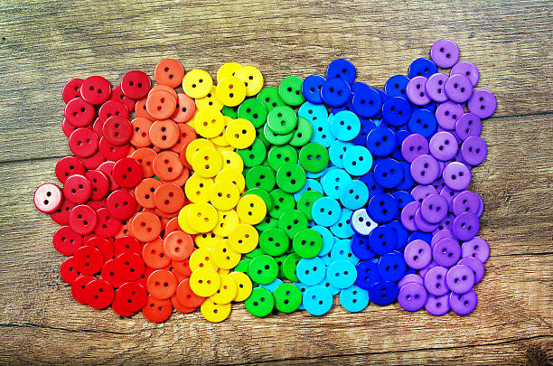 Colors of rainbow. Pattern of multicolored buttons texture background. Palette of rainbow colors. Multicolored buttons on a wooden table.