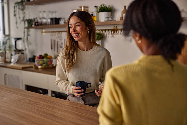 istock Two friends chat warmly in a modern kitchen, holding mugs and sharing a friendly moment 2256437134