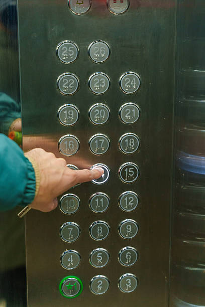 A young Asian woman presses the elevator in an office building