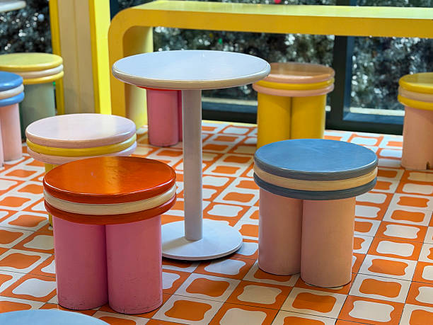 Stock photo showcases a vibrant seating area with colourful tables, stools, and chairs featuring retro patterns. The space includes pedestal tables and bench seats, creating a playful and nostalgic atmosphere