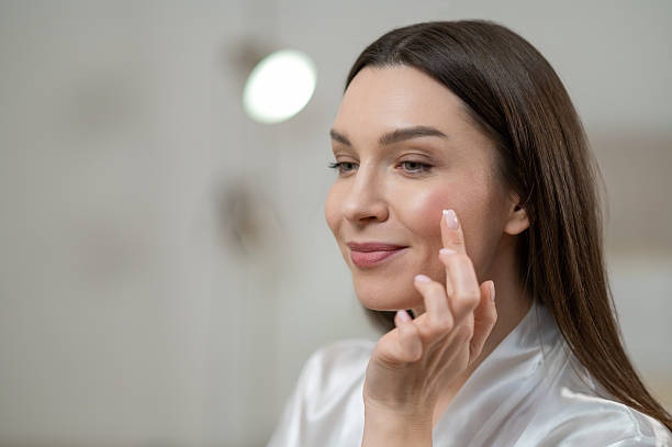 istock Young smiling woman applying hydrating cream on her face 2256452742