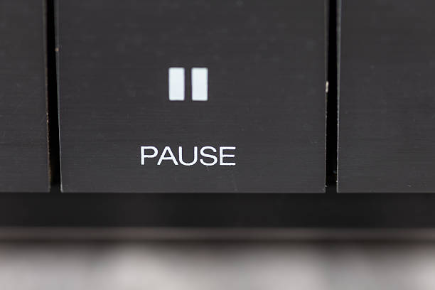 A close-up view of a car stereo featuring a prominent pause button, showcasing sleek metallic controls and a blurred dashboard. Ideal for themes of music, technology, and automotive interiors.