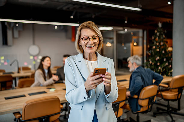 istock Mature adult businesswoman smiling while using smartphone in office 2256457047