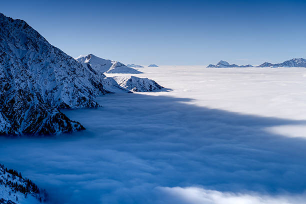 Inversion in Alps in winter, amazing landscape of snow-covered mountains, France.