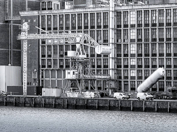 Old industrial harbor featuring a large crane, shipping containers, and a building facade, reflecting historical port activity