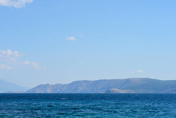 A scenic view of the rugged southeastern coastline of Krk Island across the deep blue Adriatic Sea as seen from the town of Selce.