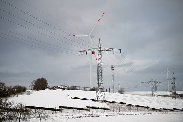 Steppe landscape covered with a thin layer of snow and a wind turbine in the middle, just after sunset