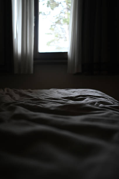 istock Bed with wrinkled sheets in dimly lit bedroom 2256467384