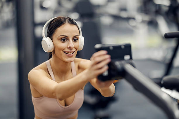 Woman streaming workout with headphones at gym