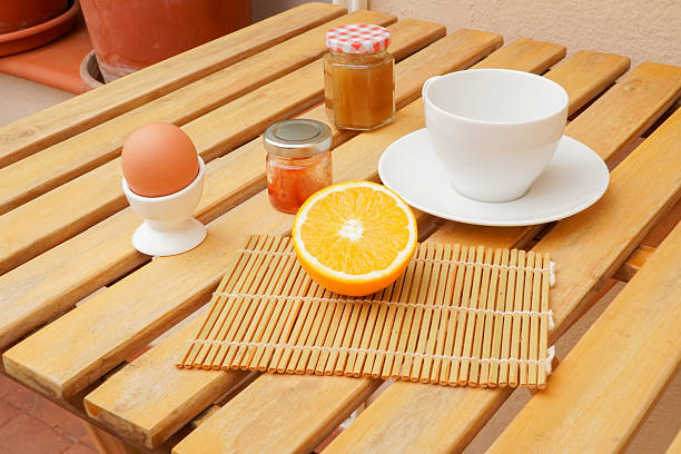 Healthy breakfast still life with orange, boiled egg and honey on wooden table