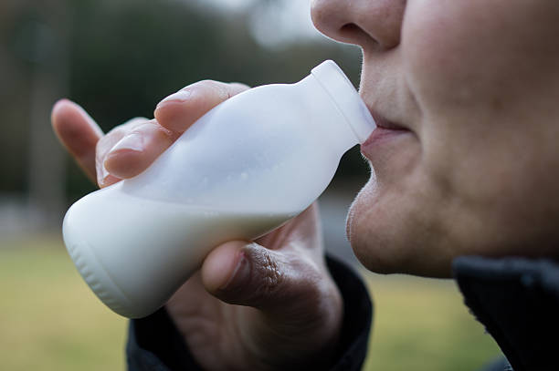 A close-up shot of a person consuming a liquid from a white plastic container, highlighting the daily use of single-use plastics and potential chemical leaching.