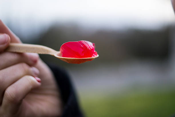 A sharp close-up of a red gelatinous dessert on a spoon, illustrating the presence of food additives and synthetic dyes in processed diets.