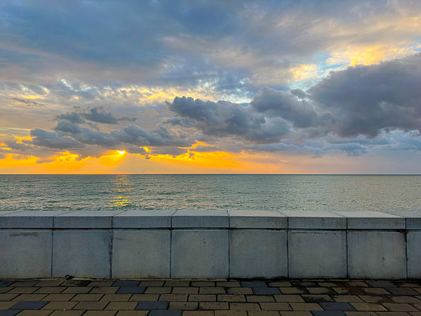 Concrete Sea Wall Overlooking Calm Ocean at Dramatic Sunset