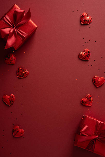 istock Romantic vertical red background showcases wrapped gift boxes and scattered hearts, creating a festive Valentine mood perfect for celebrations, greetings, gifts, and romantic occasions 2256482328