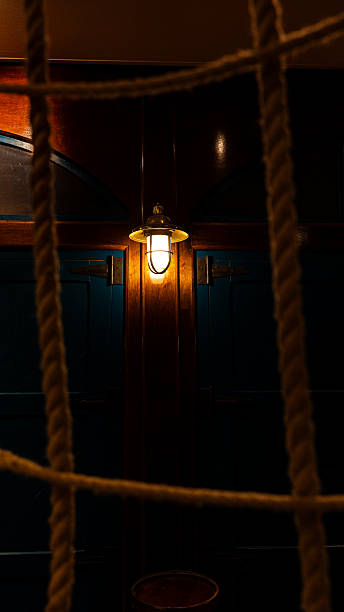 Nautical lamp casts warm light inside a boat cabin through a rope net