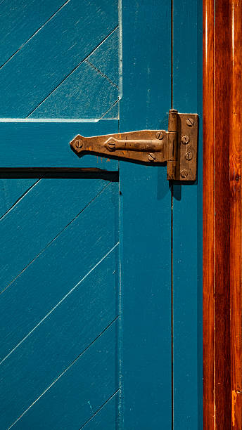 Vibrant blue door featuring a weathered metal hinge on an old wooden frame