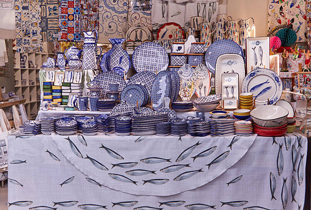 Portuguese ceramic and textile souvenirs are arranged at a market, showcasing detailed patterns and vibrant colors on various plates and bowls
