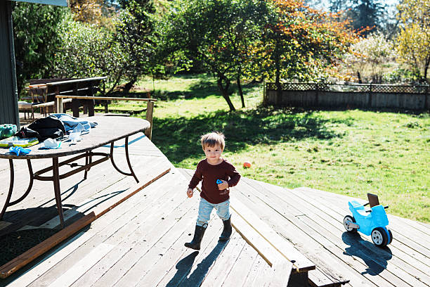 A two-year-old Eurasian boy plays independently in the backyard of his home on a sunny afternoon.