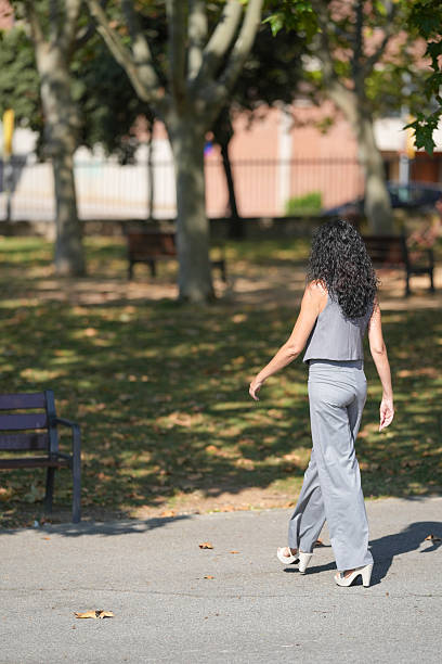 istock A woman walks down a sidewalk in a park 2256500188