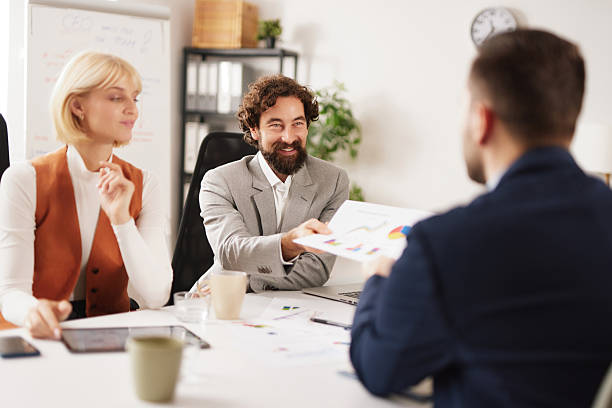 istock Business team works on ideas through discussion and sharing documents during a meeting in a modern office setting on a weekday morning 2256500234