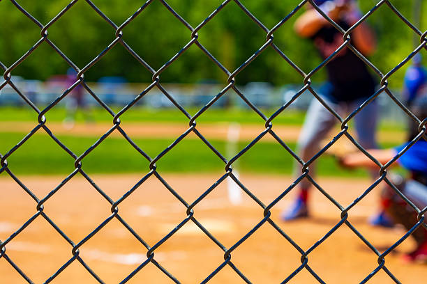Blurred baseball field viewed through fence with blurred background.