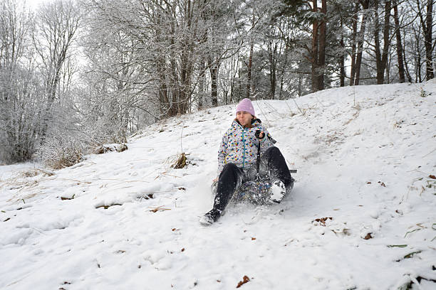 Woman rides a inflatable donut sled down a snowy slope.