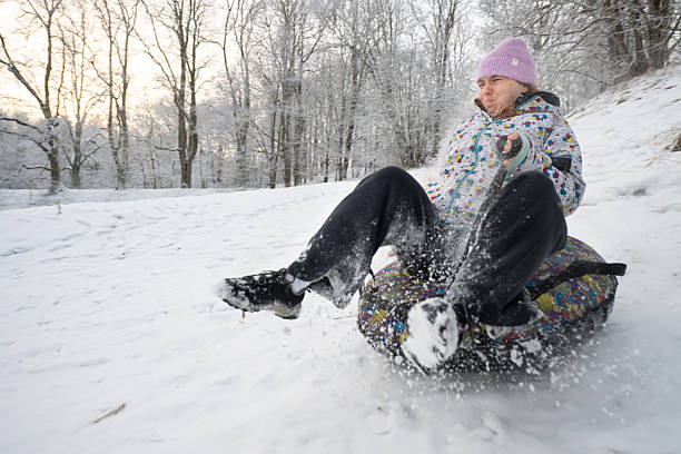 Woman rides a inflatable donut sled down a snowy slope.