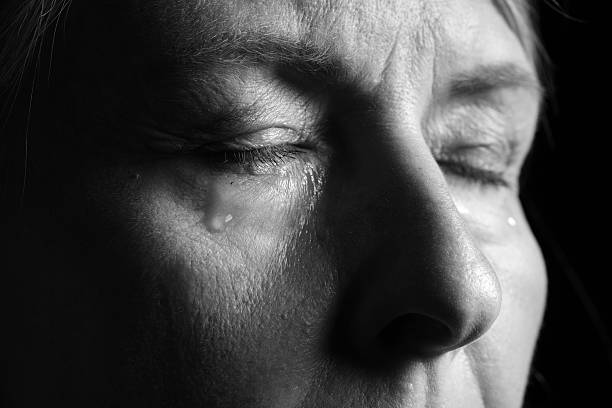 Senior woman crying on dark background, closeup. Black and white effect