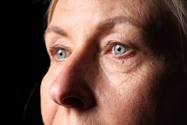 Senior woman crying on black background, closeup
