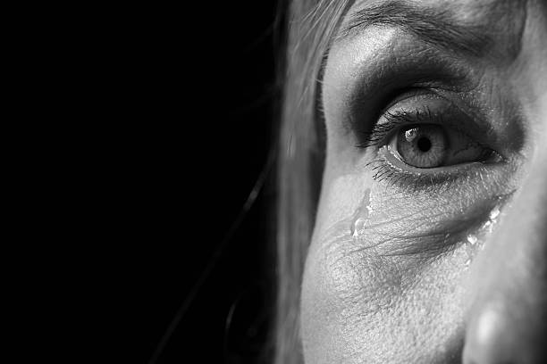 Senior woman crying on dark background, closeup. Black and white effect