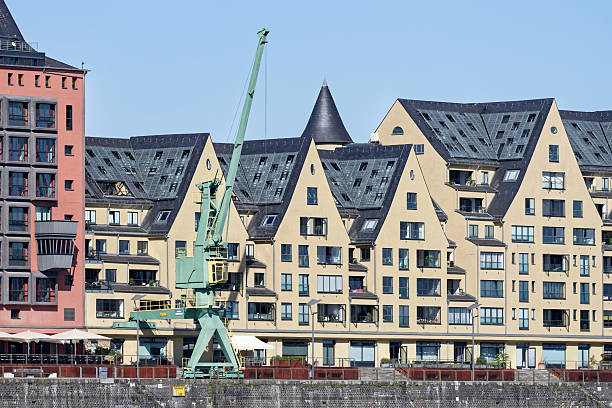 View of modern architecture at Cologne's Rheinauhafen. A restored harbor crane stands in front of exclusive residential buildings along the Rhine