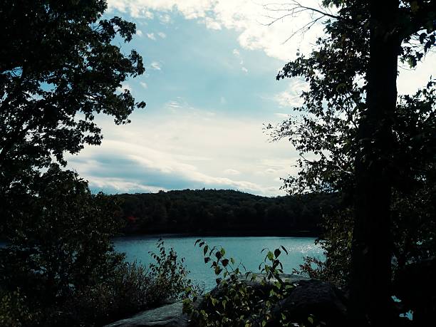 A landscape view of a filled in abandoned quarry in the woods of Harriman State Park on a sunny fall day.
