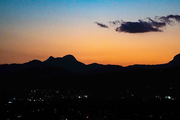 This dramatic landscape shows intense sunset colours spreading across the sky as black mountain silhouettes form a striking contrast along the horizon