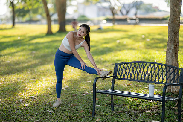 Young adult woman stretching her leg during an outdoor workout session in a park