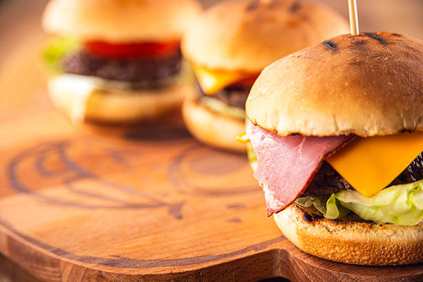 Cheeseburgers with Bacon and Lettuce on Wooden Board, Shallow Depth of Field