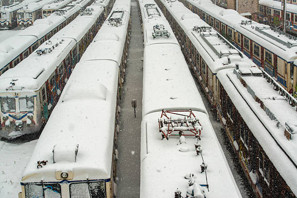 Multiple trains parked side by side at a railway yard covered in fresh snow during heavy snowfall. An overhead winter transportation scene showing urban rail infrastructure in Istanbul, Turkey.