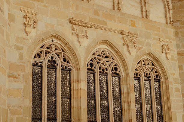 A beautifully crafted gothic windows adorns an ancient stone wall, showcasing artistic metalwork.