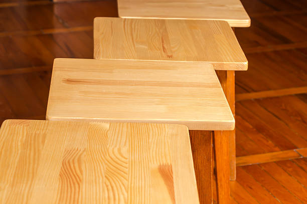 Wooden varnished square seats of four kitchen stools made with natural glued pine board of light color, view close-up in selective focus