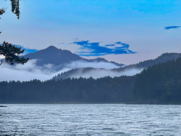 Serene Mountain Landscape with Mist Over River and Lush Forest During Early Morning.