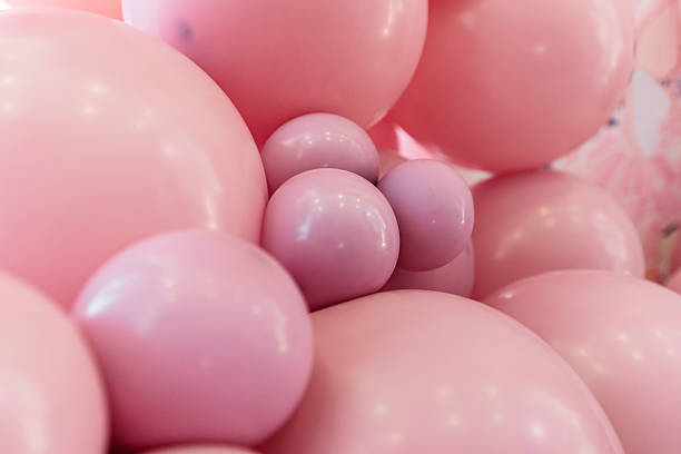 A single colorful balloon drifts high against a bright blue sky with scattered white clouds. The scene captures a light, carefree atmosphere and a sense of freedom.