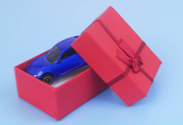 Car model in red gift box on blue background. Car as a gift concept.