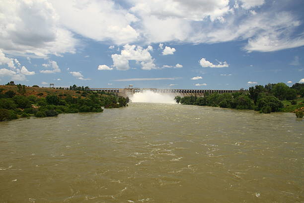 The Vaal Dam releases water through multiple open sluice gates during a period of high flooding. The dam is a critical component of South Africa’s water supply system, providing storage, flood control, and water to the Gauteng region.