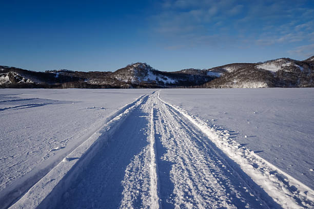 Snowmobile track marks on the snow of frozen river