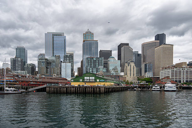 View of the Seattle waterfront featuring Pier 56 and the downtown skyline in Seattle. High-rise buildings, historic piers, and harbor waters line Elliott Bay under overcast skies, illustrating urban life, tourism, and maritime activity along the city’s shoreline.