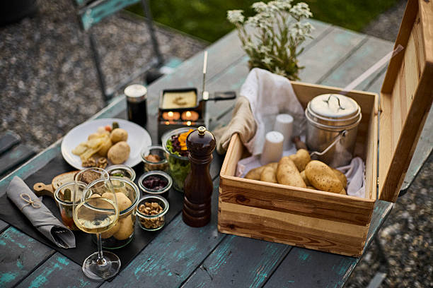 A traditional Swiss dinner with melted cheese, potatoes, and wine served outdoors at sunset. The alpine mountains in the background create a warm and cozy atmosphere, combining authentic Swiss cuisine with scenic natural beauty. Perfect for concepts of travel, gastronomy, hospitality, and European lifestyle.